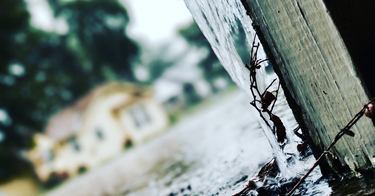 Close-up of rainwater flowing from a gutter during a storm, capturing the essence of rainy weather.