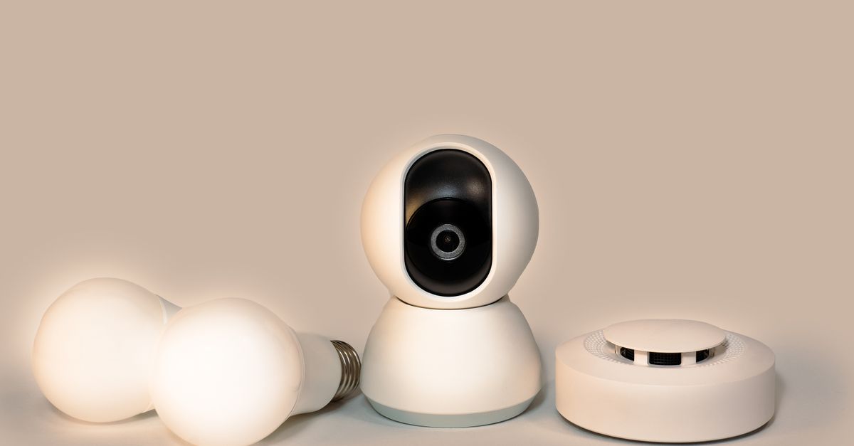 A collection of modern smart home gadgets including a CCTV camera, LED bulbs, and a smoke detector.